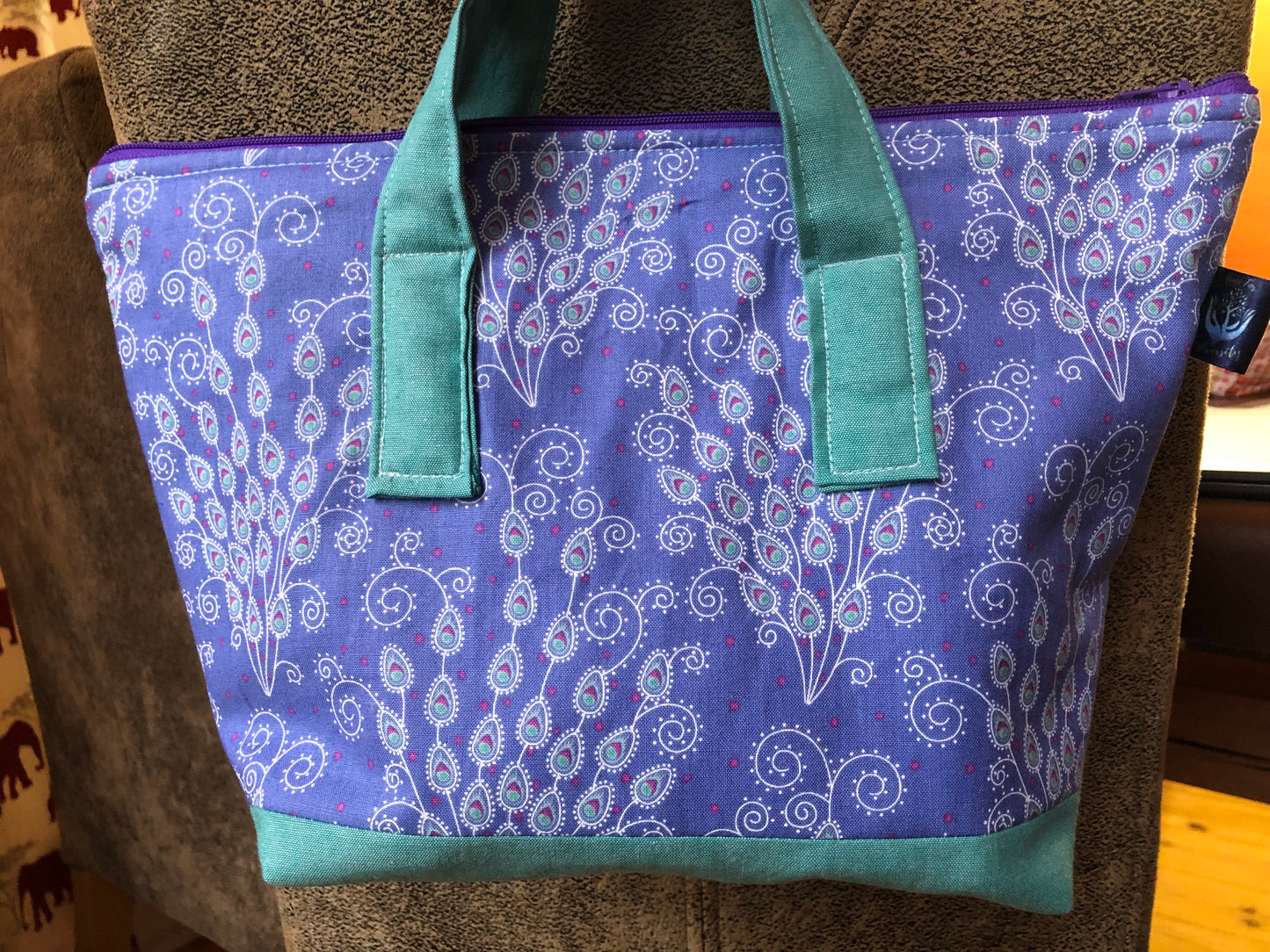 mauve and turquoise peacock feather washbag with waterproof lining and 2 interior slip pockets