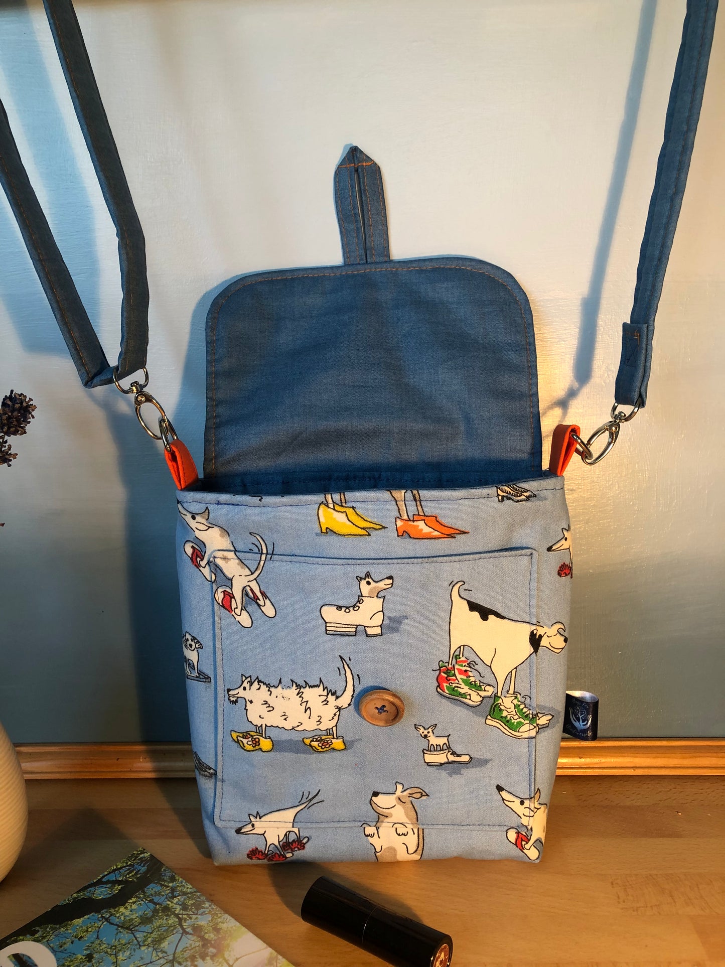 Blue cross body  bag with dog illustrations on a wooden surface