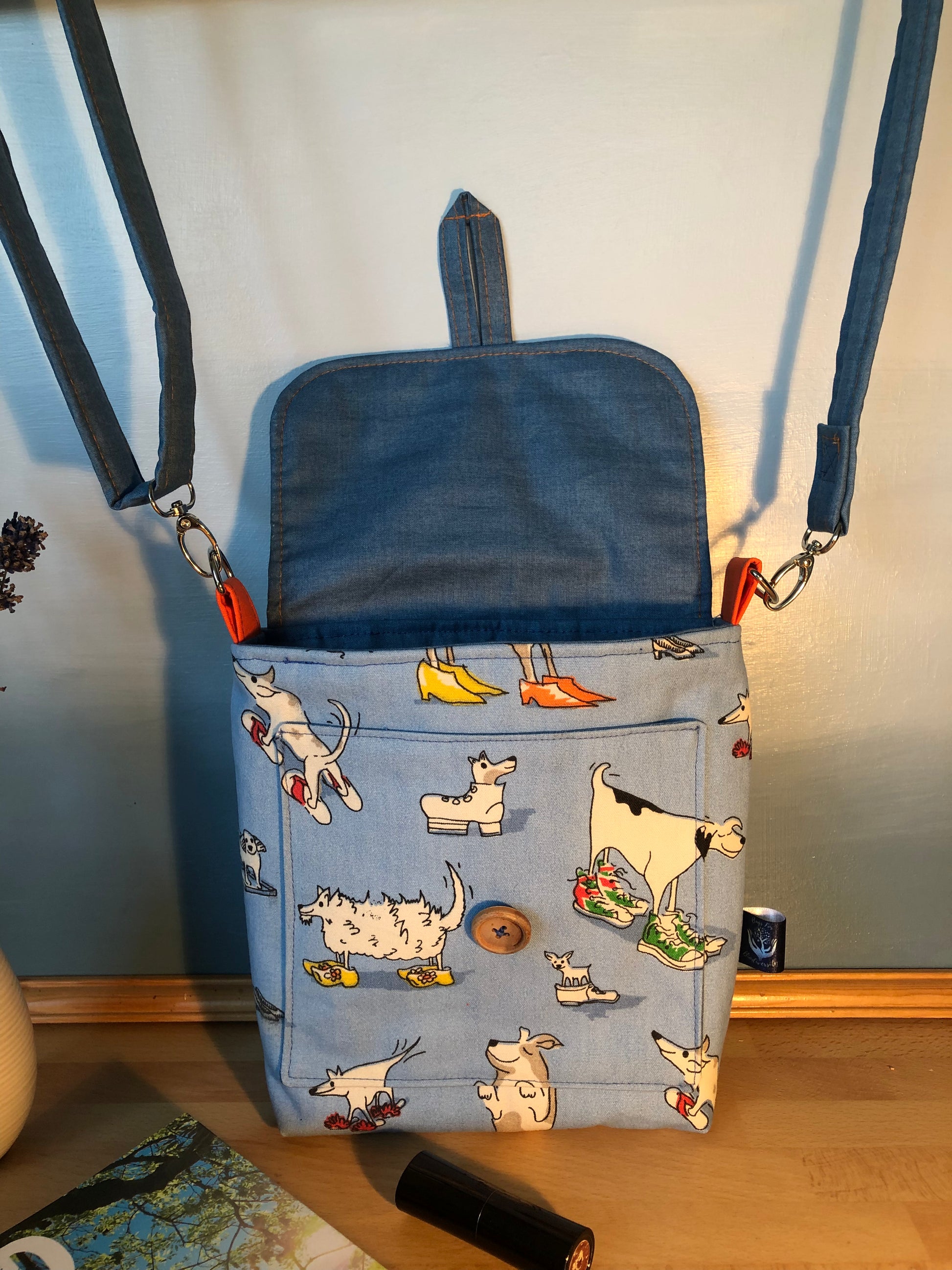 Blue cross body  bag with dog illustrations on a wooden surface