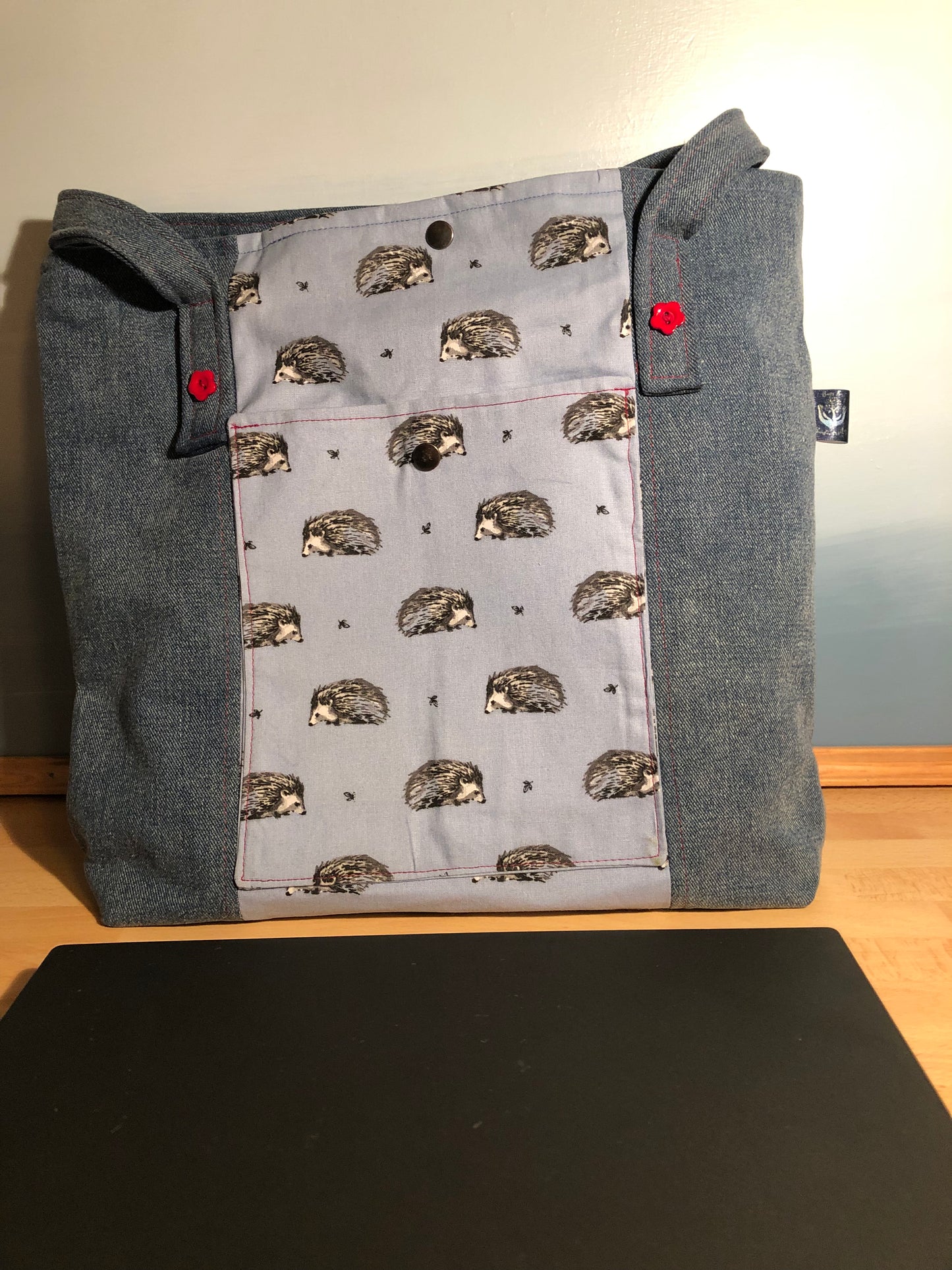 Denim shopper bag with central blue hedgehog panel. outer slip pocket, internal red zip pocket, denim slip pocket